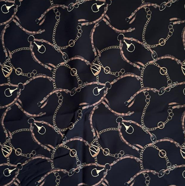 Folded Dark Navy Equestrian Chain Digital Print Cotton Fabric, showing intricate gold chain and buckle patterns, ideal for sustainable dresses, men's shirts, and luxurious home decor.