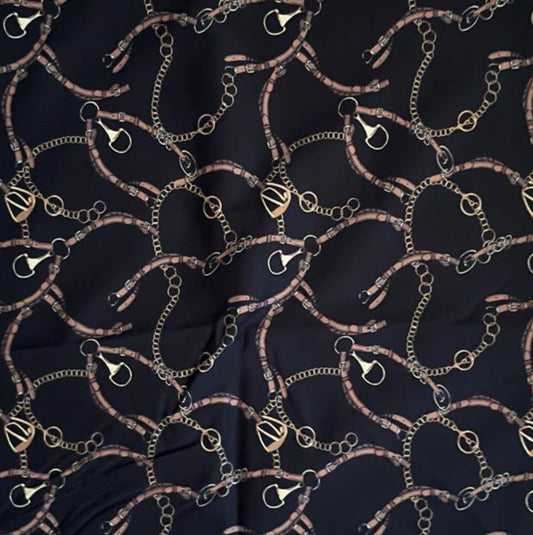 Folded Dark Navy Equestrian Chain Digital Print Cotton Fabric, showing intricate gold chain and buckle patterns, ideal for sustainable dresses, men's shirts, and luxurious home decor.